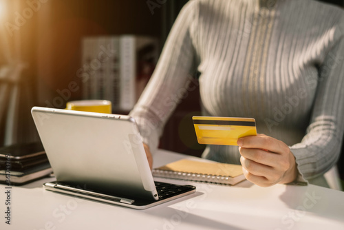 Business women use credit cards to pay through tablet at home office in the evening.