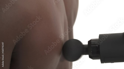 Close-up side view of a therapist treating injured back muscle (trapezius muscle) of African sportsman using professional massage gun. Sport physical therapy concept. Isolated on white background
