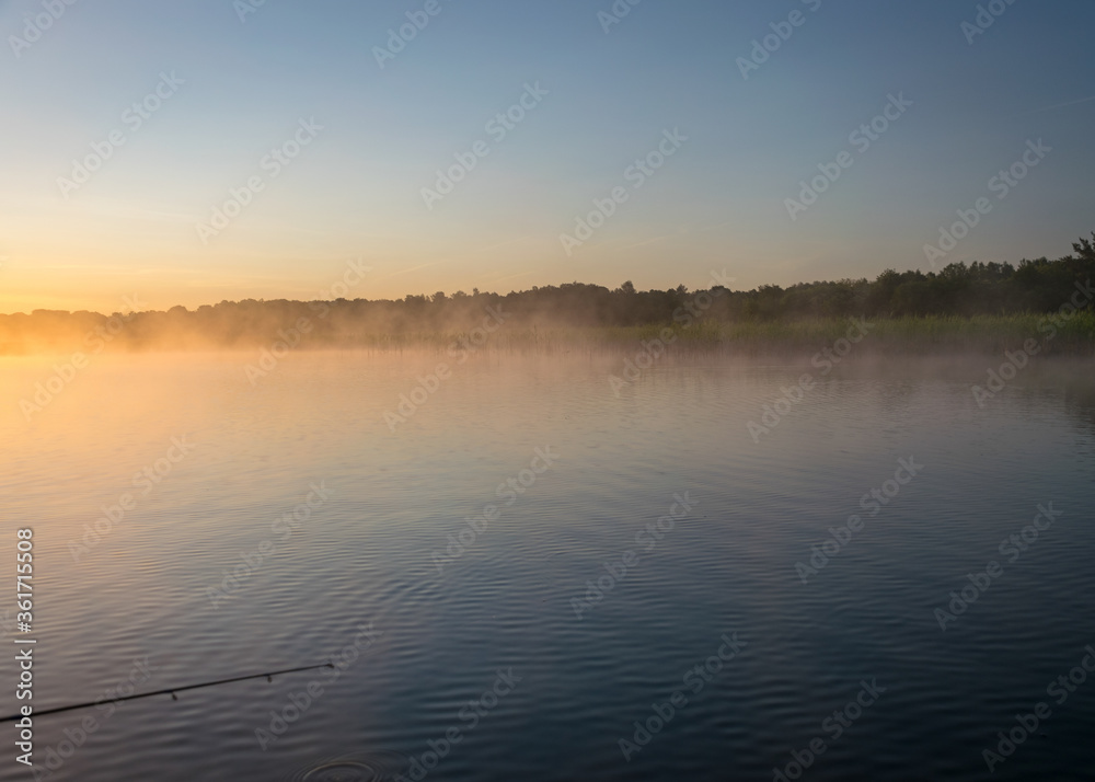 Obraz premium Foggy weather early in the morning on the lake. beautiful wallpapers. a mystical mist vibrates in the lake. summer sunrise