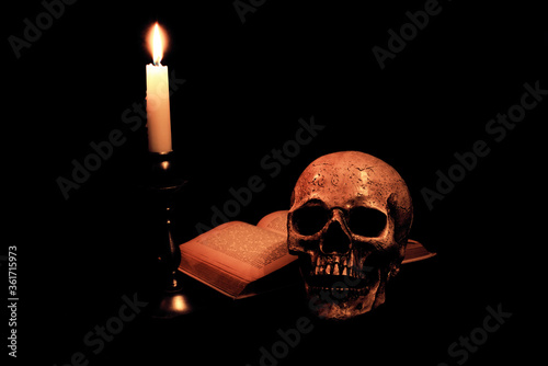 Ein Buch und Schädel im Kerzenlicht