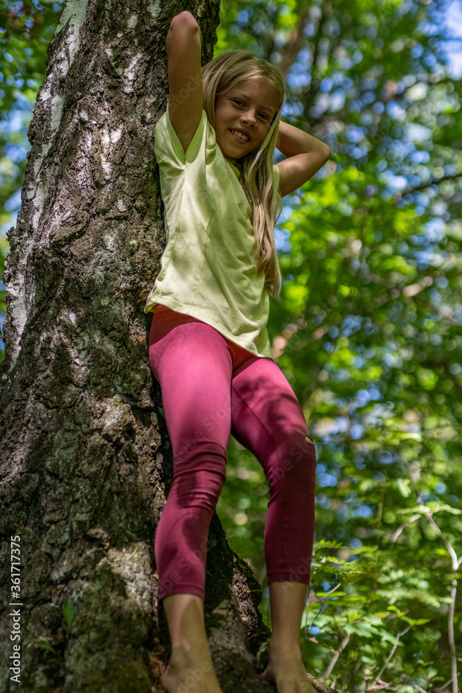 Mädchen beim unbeschwerten Sport und turnerischer Bewegen, wie Akrobatik in der Freizeit, im Wald und in der Natur. Sie trägt legere Kleidung, Shirt und Leggins.