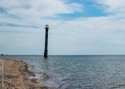 landscape with an abandoned sloping lighthouse "Kiipsaare lighthouse" on the Baltic Sea. Clear water and blue sky with white clouds. Harilaid Nature Reserve, Estonia, Baltic Sea