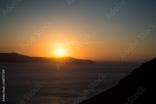 Sunset over the sea and the south end of the island of Santorini, Greece. View from Fira, the capital
