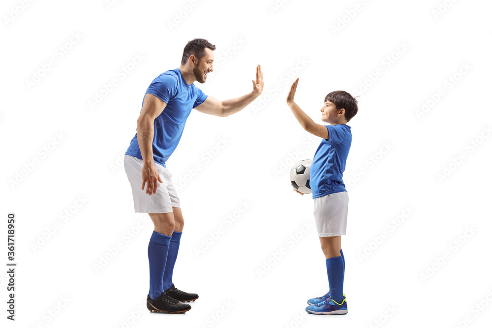 Adult football player gesturing high five with a junior football player Adult football player gesturing high five with a junior football player