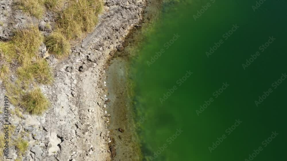 An almost chemical green colored lake with a rocky beach seen from above
An almost chemical green colored lake with a rocky beach seen from above