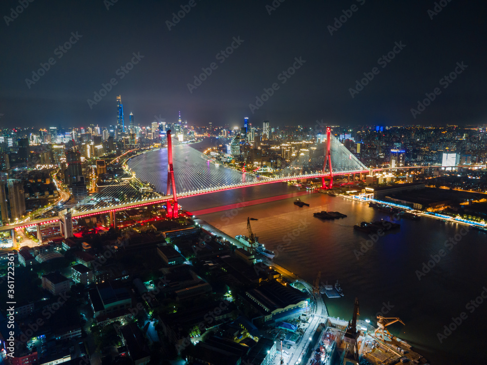 Naklejka premium Aerial view of Shanghai cityscape & night-scape. Futuristic modern city view. Downtown Lujiazui District and Yangpu bridge in the night. Neon light and traffic lights. Drone point of view in sky