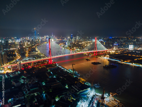 Aerial view of Shanghai cityscape & night-scape. Futuristic modern city view. Downtown Lujiazui District and Yangpu bridge in the night. Neon light and traffic lights. Drone point of view in sky