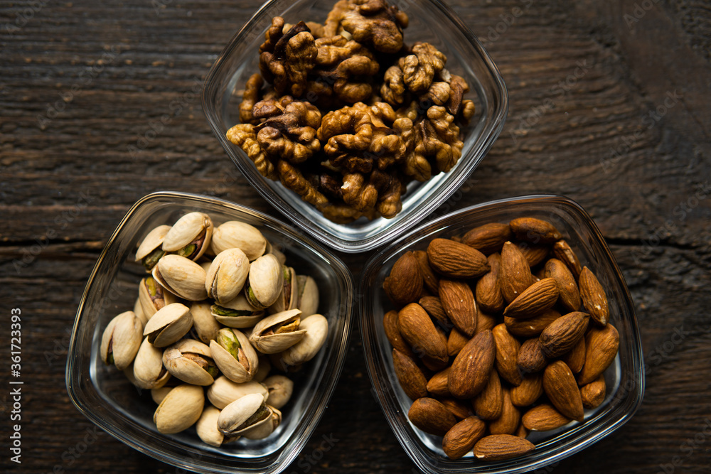 Almond, pistachio and walnut in a small plates which standing on a vintage wooden table. Nuts is a healthy vegetarian protein and nutritious food. Almond, pistachio and walnut in a small plates which standing on a vintage wooden table. Nuts is a healthy vegetarian protein and nutritious food.