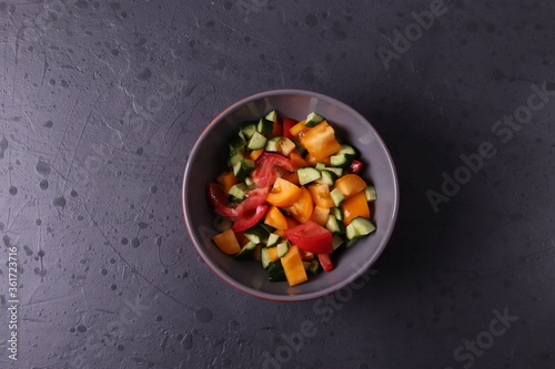a bowl of vegen vegetable salad on dark grunge stone background