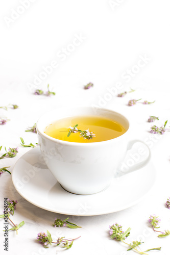 A Cup of tea with thyme flowers on a white background. The view from the top. Concept of folk medicine. Herbal drink.