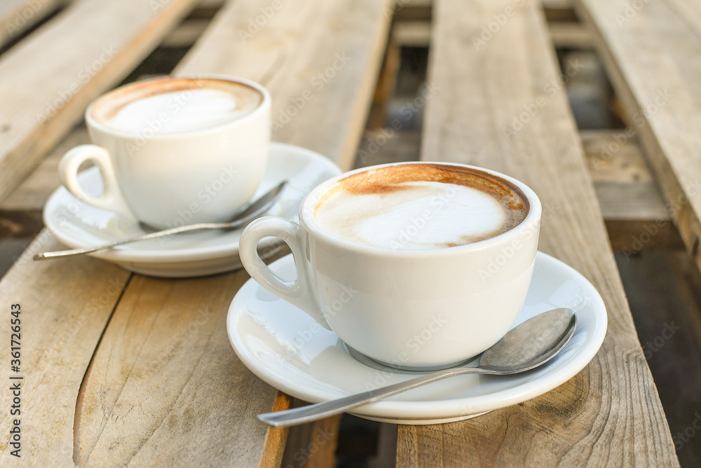 Two cups of cappuccino on wooden background. morning coffee for couple in love. selective focus Two cups of cappuccino on wooden background. morning coffee for couple in love. selective focus