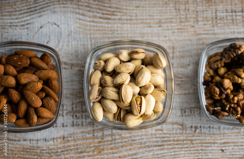 Almond, pistachio and walnut in a small plates which standing on a vintage white table. Nuts is a healthy vegetarian protein and nutritious food.