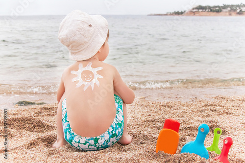 The sun drawing sunscreen on baby (boy)  back.