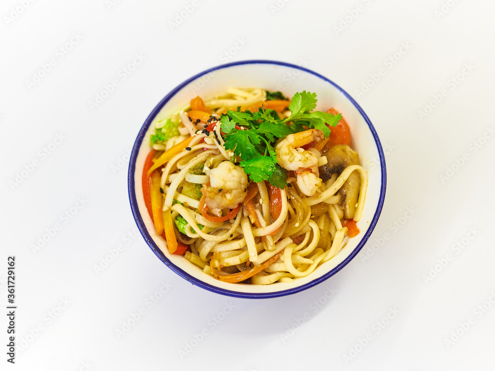 Udon noodles with seafood in a plate on a white surface. With vegetables greens Udon noodles with seafood in a plate on a white surface. With vegetables greens
