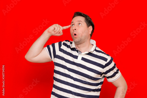 35s caucasian Man with finger near his head thinking something over trendy red wall. © ARVD73