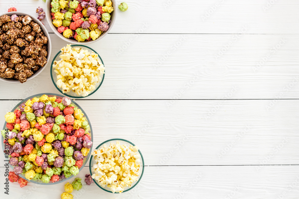 Colorful popcorn in bowl on white desk top-view copy space