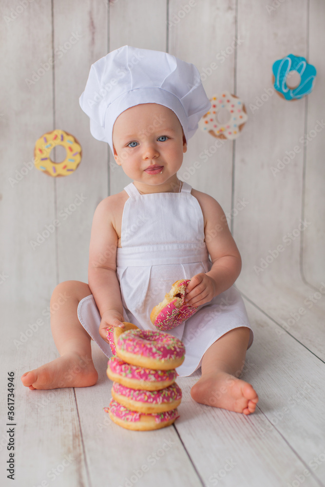 One year old baby girl celebrates her birthday. Doughnut background. Handmade paper cutout garland. One year old baby girl celebrates her birthday. Doughnut background. Handmade paper cutout garland.