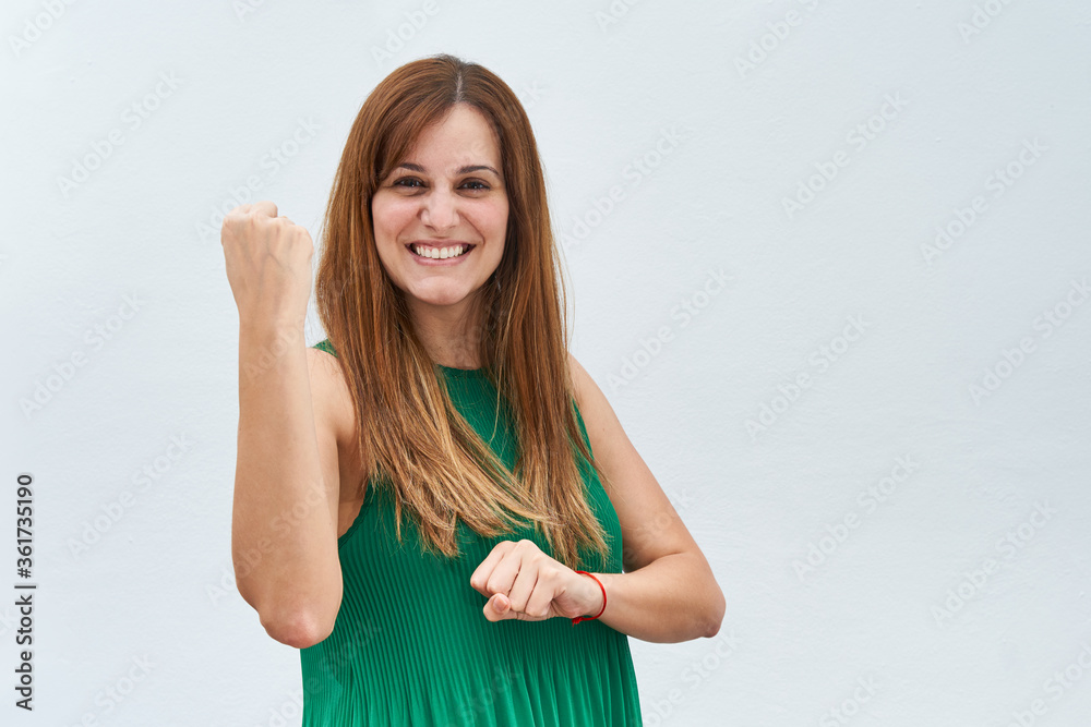 Fototapeta premium Happy young woman making the gesture of strength isolated on a white background.