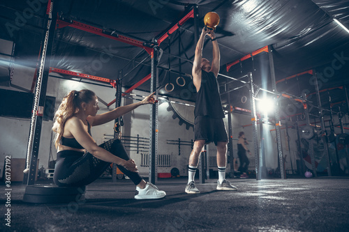 Beautiful young sporty couple workout in gym together. Caucasian man training with female trainer. Concept of sport, activity, healthy lifestyle, strength and power. Working out with weights. © master1305