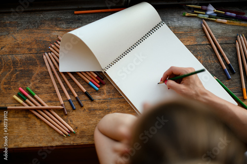 Top view on the hand of woman who draws with colored pencils in sketchbook. photo