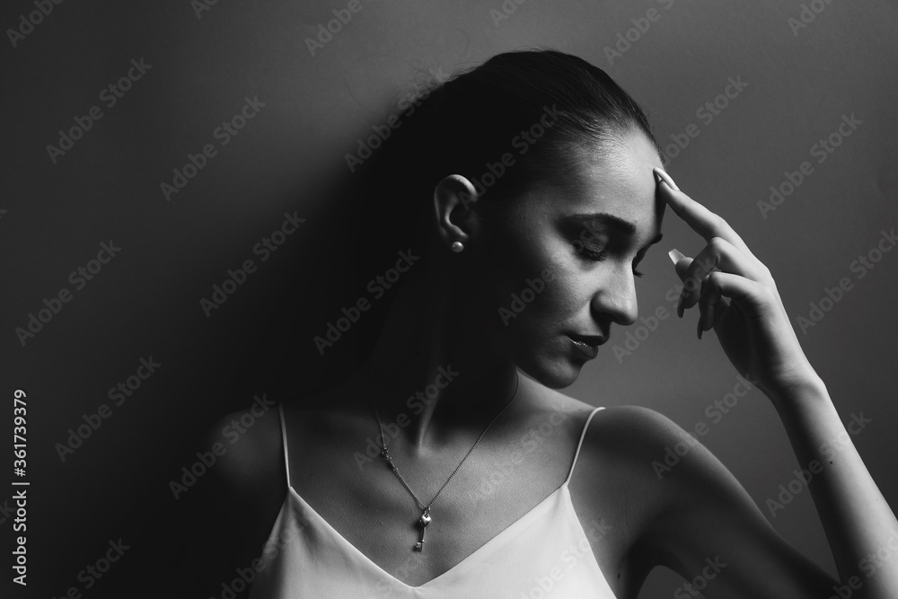Obraz premium Beauty fashion portrait of a pretty young woman with eyes closed. Black and white photo. Woman in a tshirt posing in the studio, head turned to the side