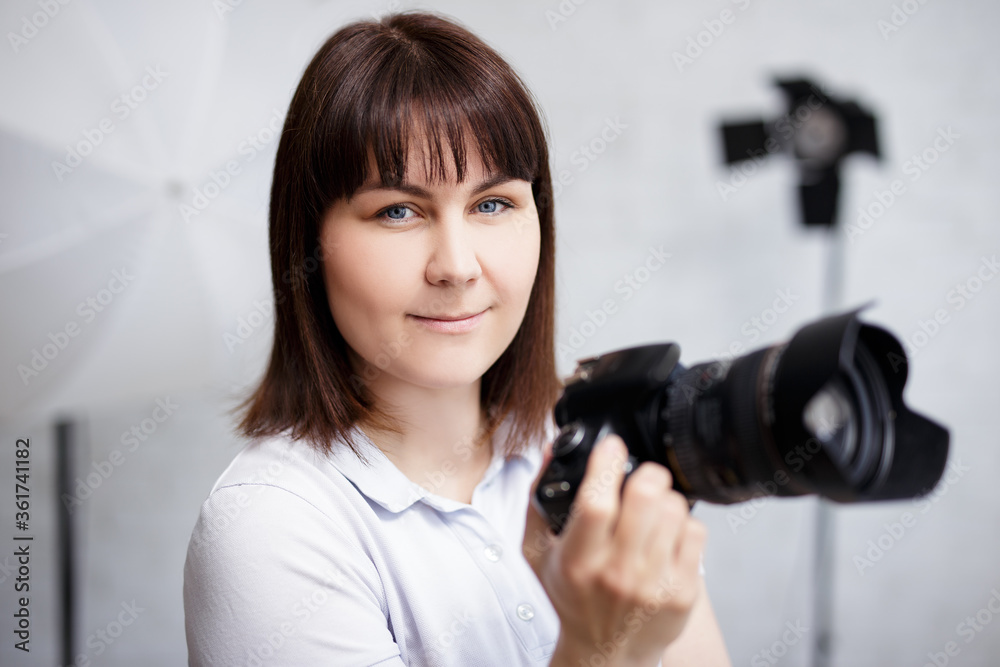 portrait of young female photographer posing with camera in her studio