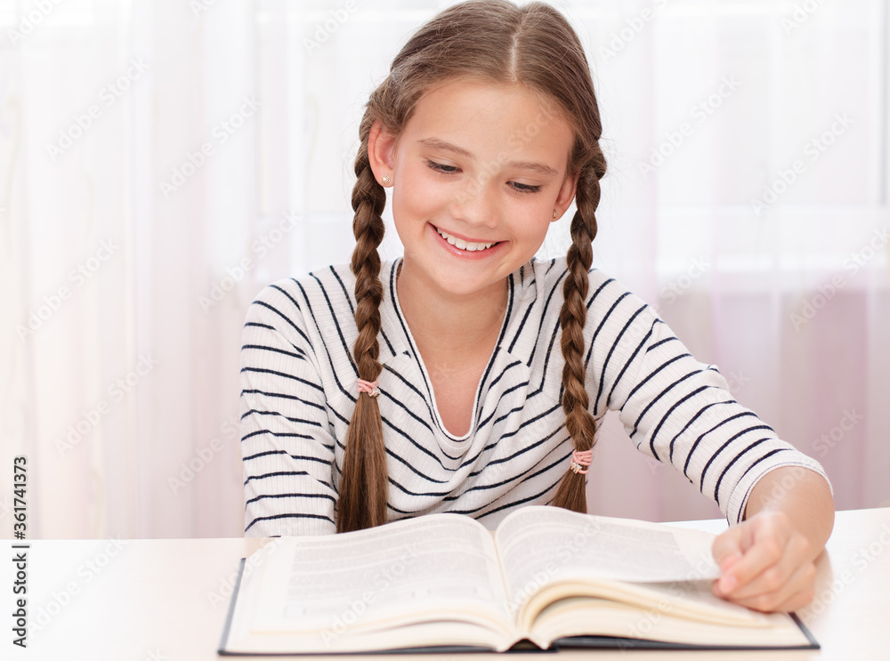 Education and school concept. Child is sitting at the desk and reading a book Education and school concept. Child is sitting at the desk and reading a book