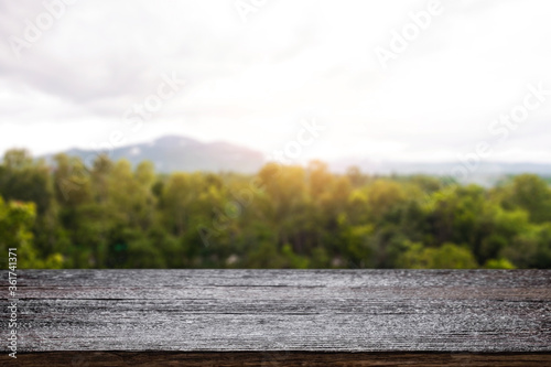 Empty wooden desk space and blurry background of mountain or hill.