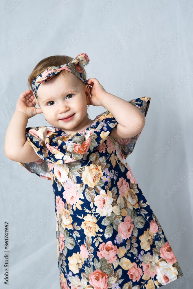 A girl in a Russian folk dress with flowers posing in front of a photographer adjusts her head scarf A girl in a Russian folk dress with flowers posing in front of a photographer adjusts her head scarf
