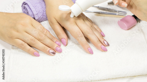 The manicurist applies a moisturizer to the client's hand. SPA manicure, procedure, moisturizing. Hand lotion, cream. Skin care. Beauty salon. Manicure concept. Beauty nails. Soft skin. Cosmetic cream