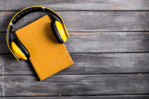 audio book concept with headphones on wooden table from above copy space