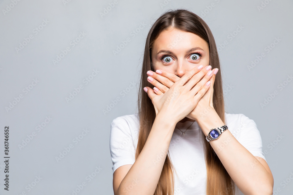 Portrait of young woman covering mouth with hand on white background Portrait of young woman covering mouth with hand on white background