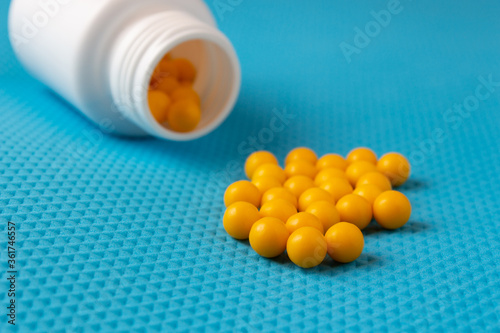 Yellow round pills with white bottle on a blue background