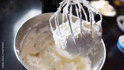 Fotografia, Obraz Whipped cream being prepared in dark kitchen. White cloudy cream