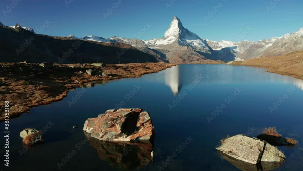 Traveler on the shore of Stellisee lake. Reflection of Matterhorn peak in the watter surface. Aerial view of Swiss Alps, Zermatt location, Valais canton, Switzerland, Europe.