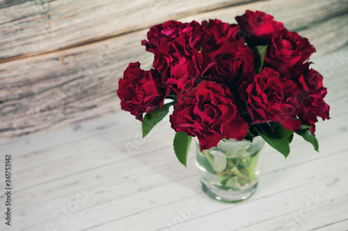 Fototapeta Naklejka Na Ścianę i Meble -  Dark red roses in vase on gray wood background with copy space.