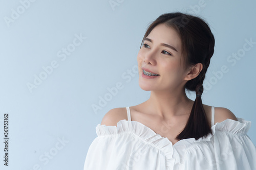 happy smiling woman with teeth braces or orthodontics dental braces looking up to blank space; cosmetic dental care concept