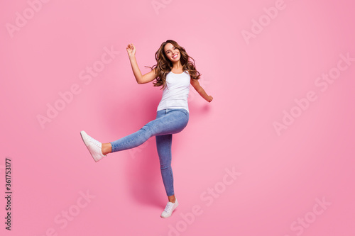 Full body photo of crazy excited lady good mood raise leg hands walking street warm day weather summer time wear white casual singlet jeans shoes isolated pink color background