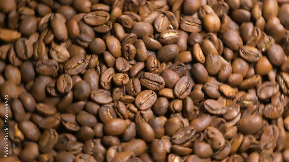 Freshly roasted aromatic coffee beans spin in slow motion top view Freshly roasted aromatic coffee beans spin in slow motion top view