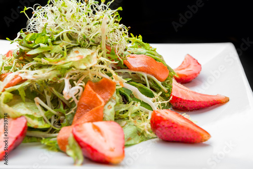 Strawberry, avocado, lettuce salad with cashew nuts on plate