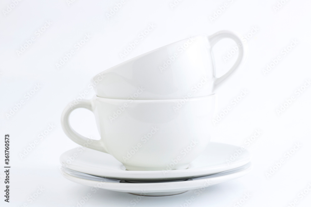 White cups and saucers stacked on a white background. Copy space White cups and saucers stacked on a white background. Copy space