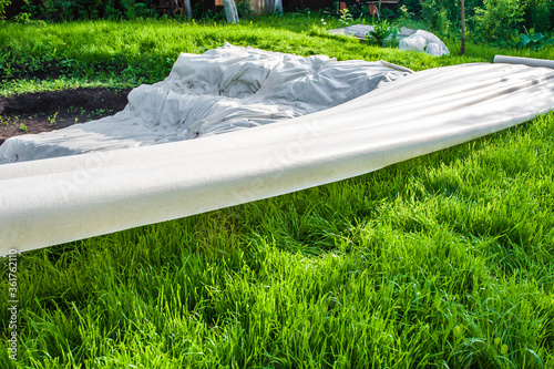 A canvas of white geotextile lies on the green grass outside