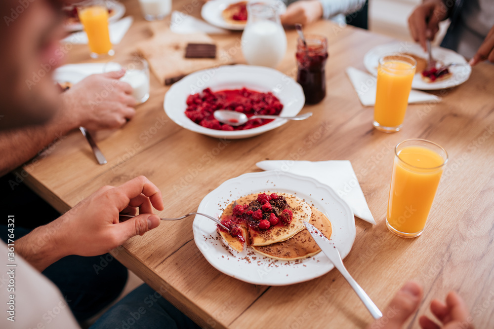 Eating homemade pancakes with friends at wooden table. Eating homemade pancakes with friends at wooden table.