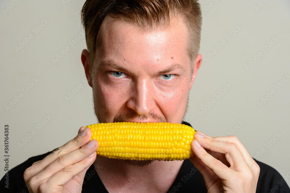 Face of young handsome man eating corn cob Face of young handsome man eating corn cob