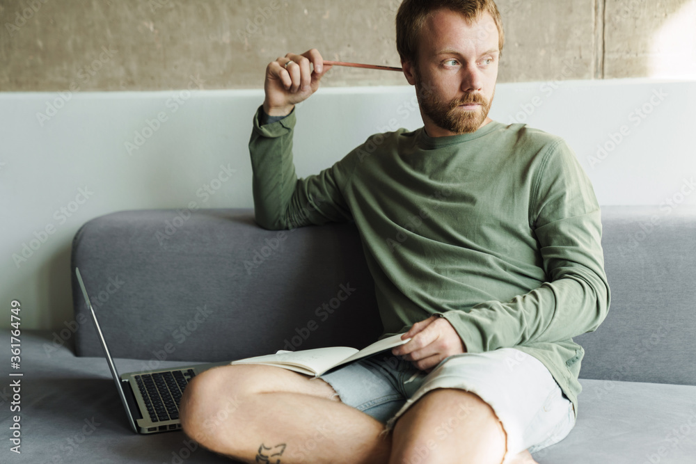 Fototapeta premium Photo of thinking man working with laptop and writing down notes