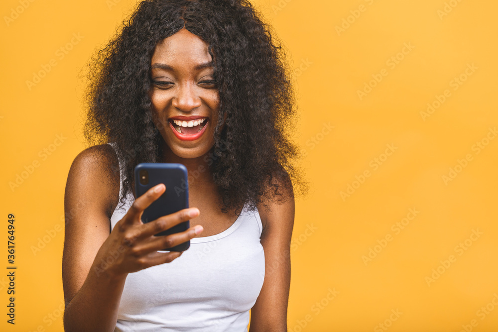 Portrait of her she nice attractive lovely winsome focused cheerful cheery wavy-haired african american black girl holding in hands phone chatting on web isolated over yellow background. Portrait of her she nice attractive lovely winsome focused cheerful cheery wavy-haired african american black girl holding in hands phone chatting on web isolated over yellow background.