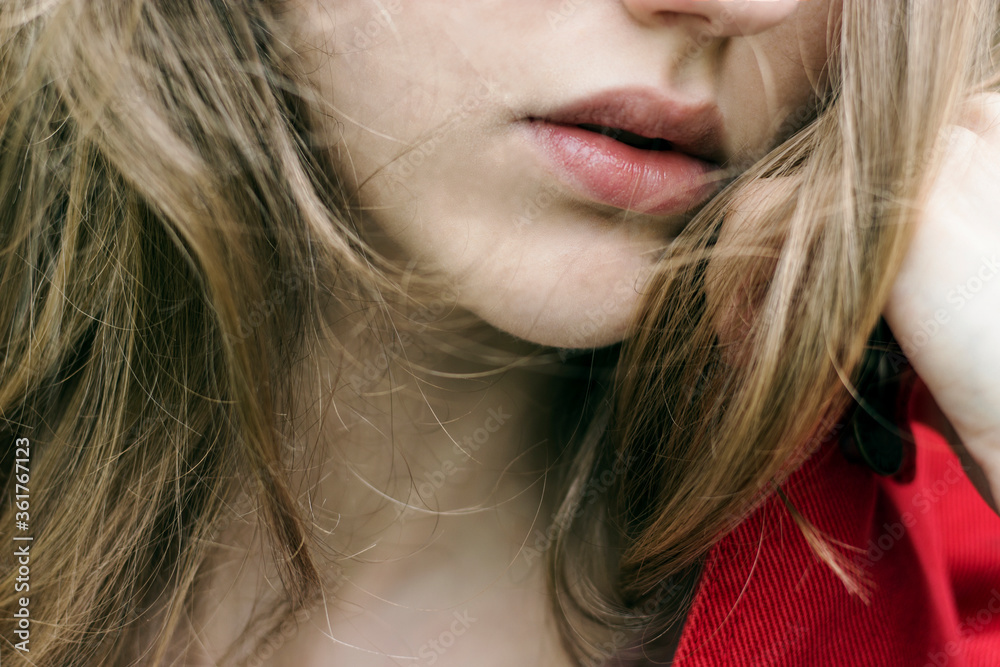Young beautiful woman's full lips with blonde hair. Nude lipstick/balm, lip care. Young beautiful woman's full lips with blonde hair. Nude lipstick/balm, lip care.