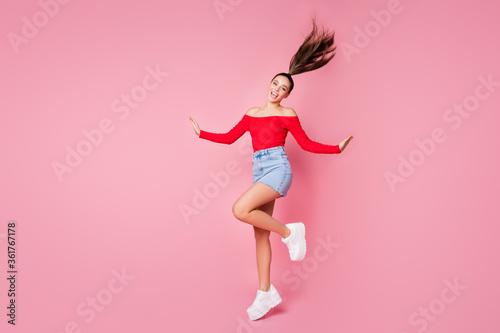 Full length profile photo of pretty funky lady rejoicing students disco party jumping excited wear red open shoulders shirt mini denim skirt shoes isolated pastel pink color background