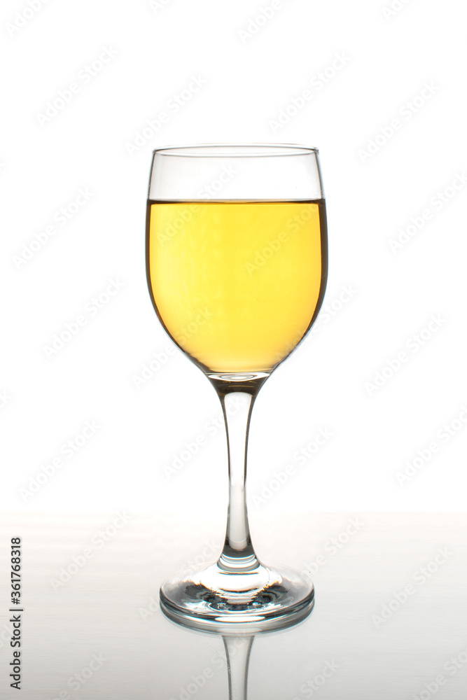 Glass of white wine with reflection on a white background Glass of white wine with reflection on a white background