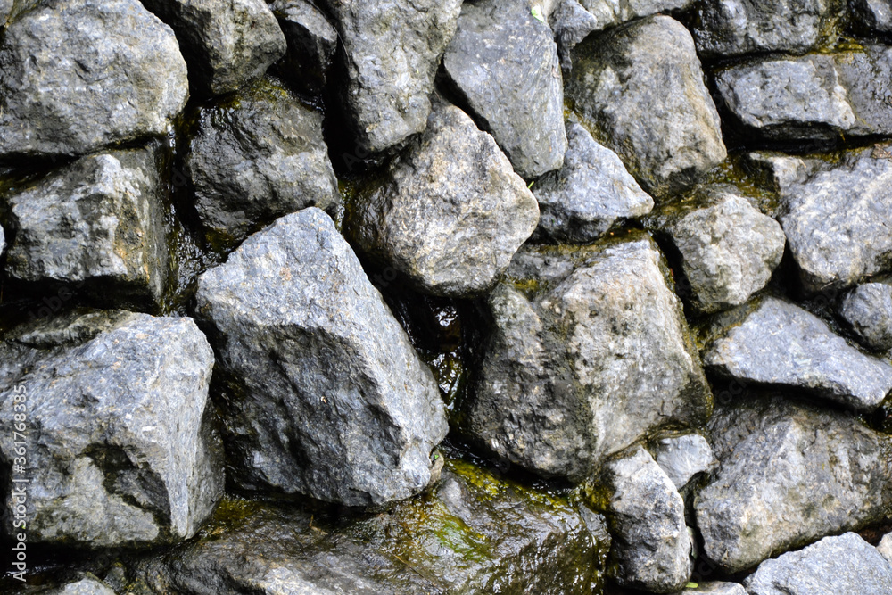 Rocks wall background. Stones wall texture. Artificial waterfall made with natural grey stones. Outdoor nature.